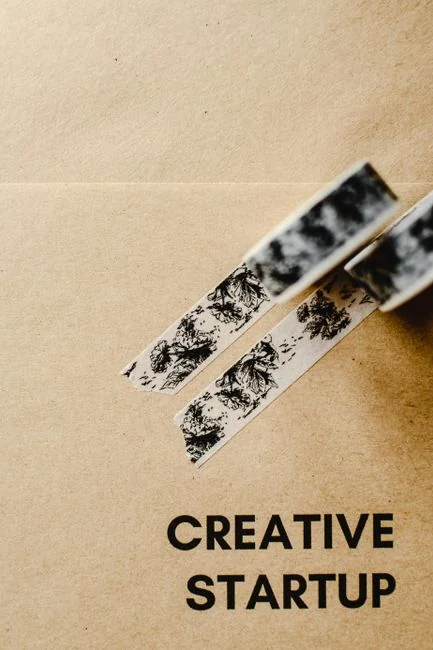 Close-up of an artist designing fashion sketches while seated at a desk indoors.